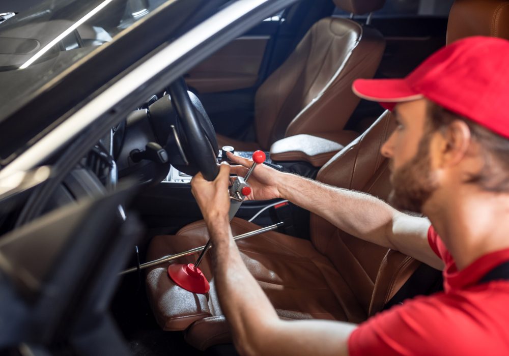 Man holding steering wheel crouched near car